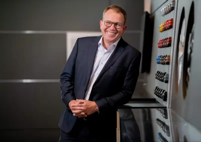 Geschäftsmann im Anzug steht lächelnd in moderner Unternehmensumgebung