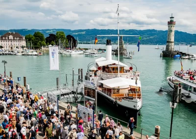 Veranstaltung am Hafen von Lindau mit Schiff, Besuchern und Leuchtturm am Bodensee