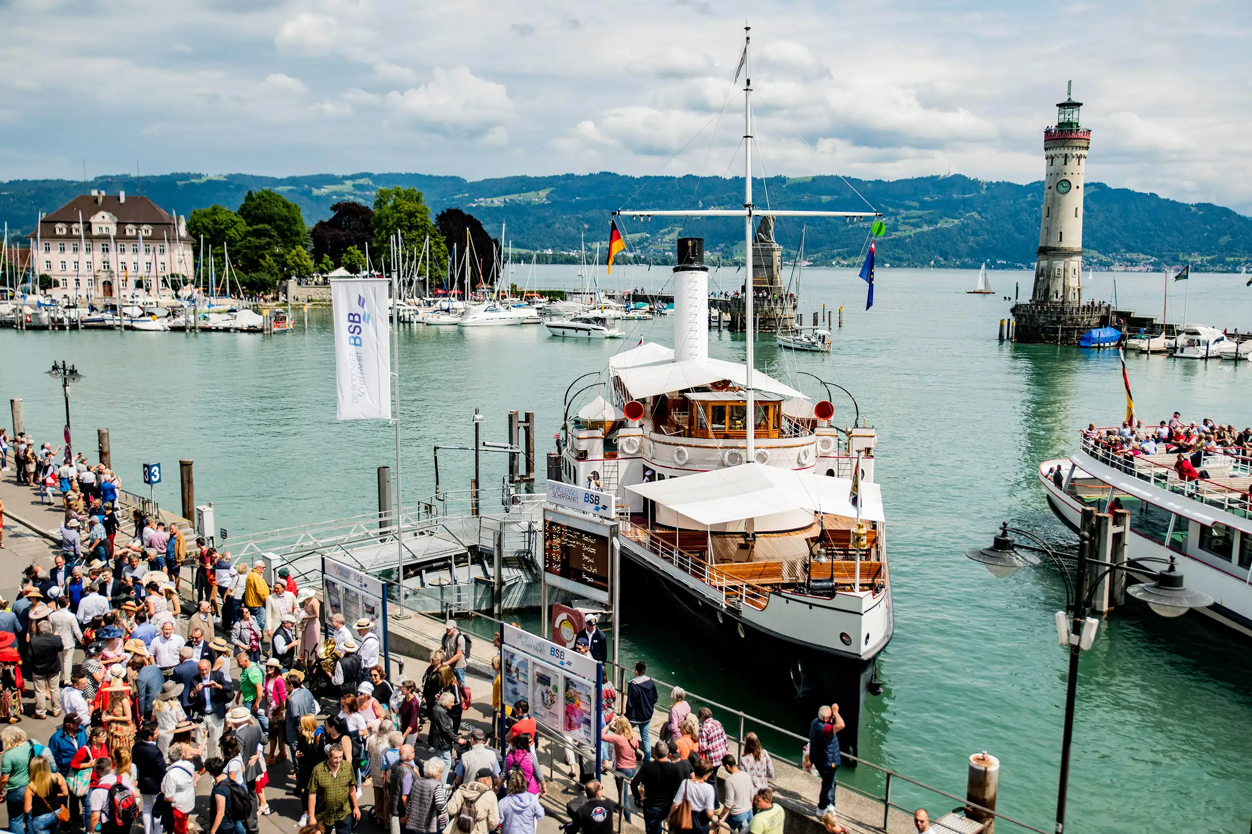 Veranstaltung am Hafen von Lindau mit Schiff, Besuchern und Leuchtturm am Bodensee