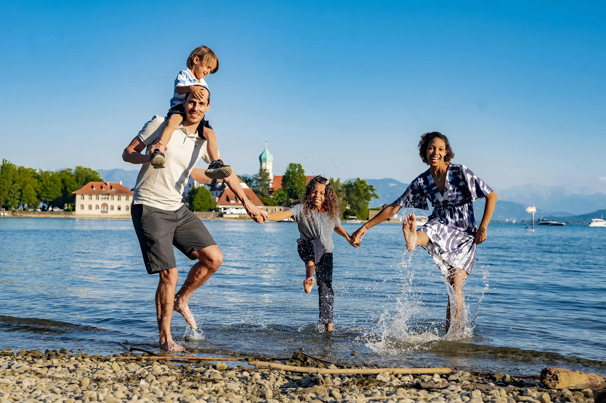 Familie mit zwei Kindern spielt im Wasser am Bodensee – natürliche Familien- und Peoplefotografie von Phototree