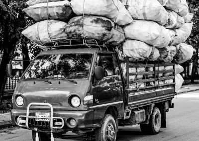 Kleiner Lastwagen transportiert große Ladung Säcke auf Straße Schwarz-Weiß