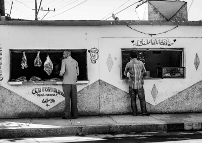 zwei Männer vor Metzgerei und Cafeteria Schwarz-Weiß Straßenfotografie