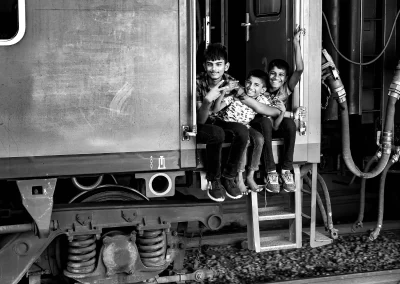 Drei Kinder sitzen lachend an einem Zug Schwarz-Weiß