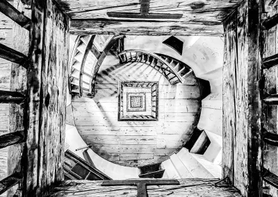 Blick von oben auf eine spiralförmige Holztreppe mit geometrischen Linien Schwarz-Weiß